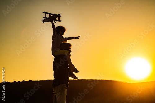 Sunset silhouette of child and dad playing. Kid pilot aviator and daddy dreams of traveling. Happy boy child.