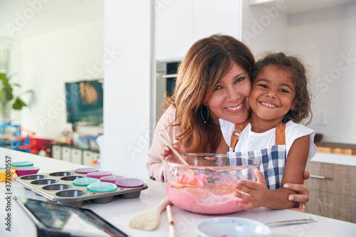 Portrait Of Hispanic Grandmother And Granddaughter Having Fun In Kitchen At Making Cake Together