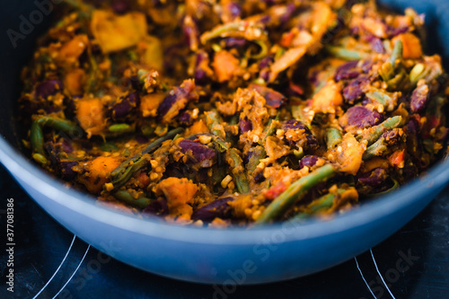 plant-based food, vegan mixed vegetables and red kidney beans getting sauteed in pan on stove