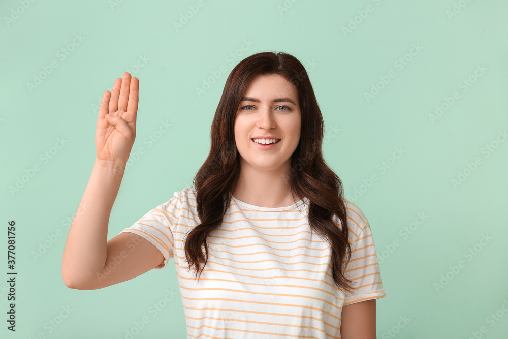 Young deaf mute woman using sign language on color background Young deaf mute woman using sign language on color background