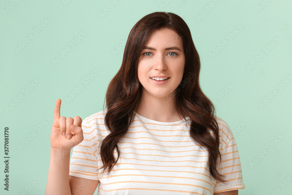 Young deaf mute woman using sign language on color background Young deaf mute woman using sign language on color background