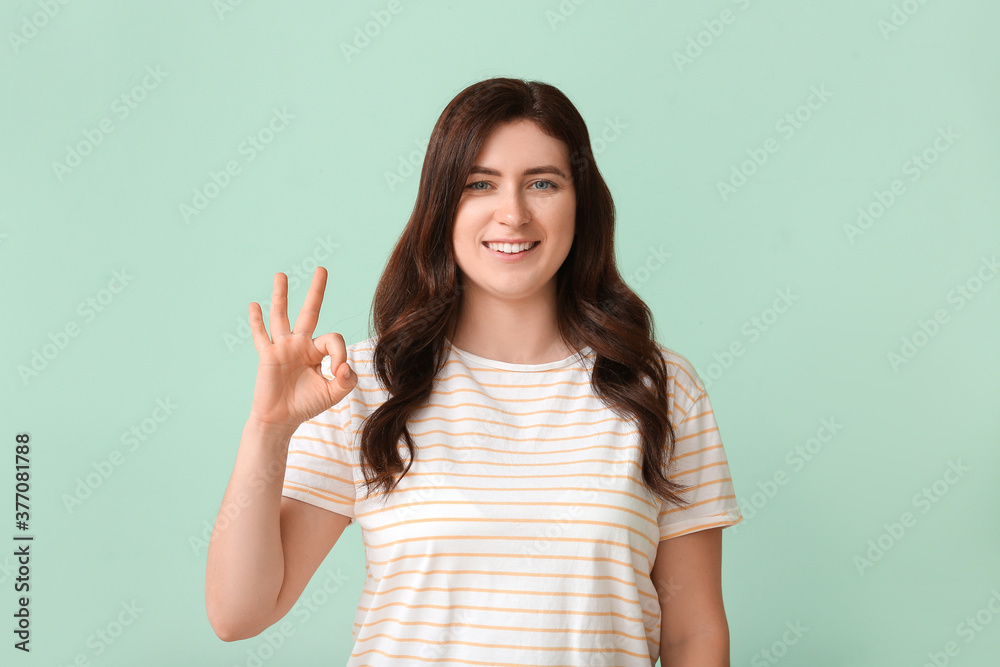 Young deaf mute woman using sign language on color background Young deaf mute woman using sign language on color background