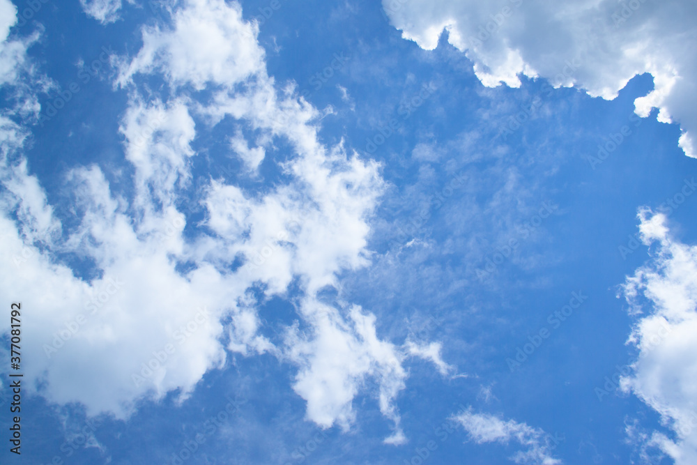 Obraz premium White fluffy clouds in a bright blue sky on a sunny day.