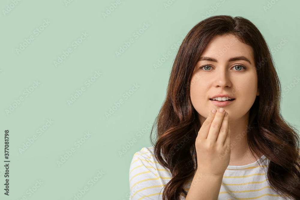 Young deaf mute woman using sign language on color background Young deaf mute woman using sign language on color background