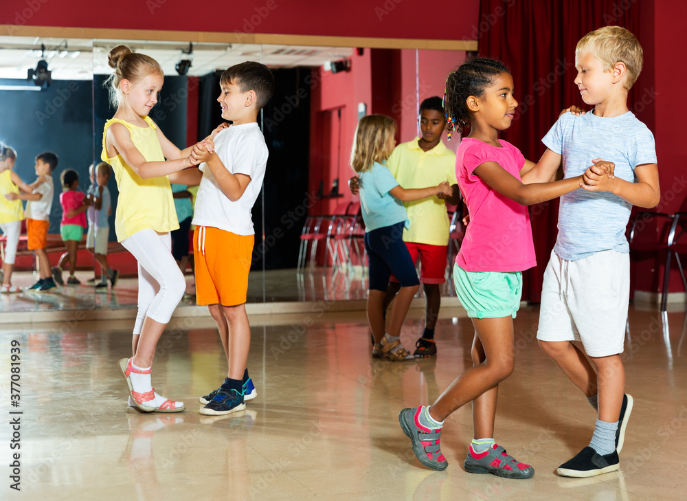 Positive children primary school trying dancing of partner dance in modern dance studio
