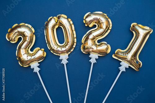 Golden numbers 2021 from new year's balls of yellow metallic color on a blue background.