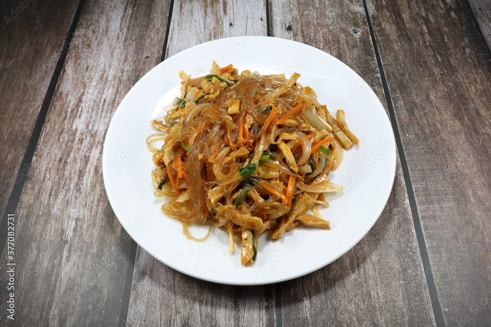 Traditional Spicy salad Korea noodle mixed with fried pork sausage,sliced onion, carrot and tofu seasoning with Gochujang sauce (Local Korea sauce) on the plate. Famous street food ancient menu. 