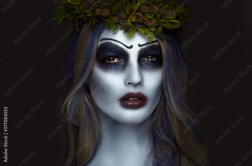 Portrait of a horrible scary Corpse Bride in wreath with dead flowers, halloween makeup