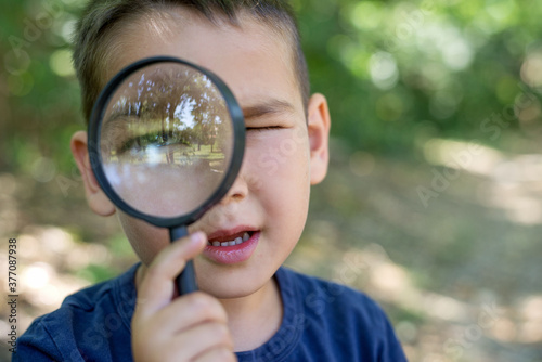 Little boy with magnifying glass in park