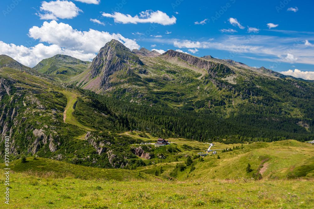 Panorama picture over Passo Rolle in the Italian Alps and the surrounding meadows, forests and Dolomite peaks taken at the end of summer. Trentino, Italy