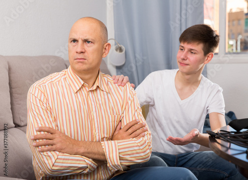 Fototapeta Naklejka Na Ścianę i Meble -  Young teenage guy trying to talk with his offended father