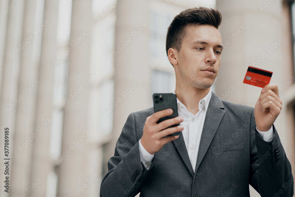 portrait of a smart man of European appearance Manager looks at the Bank card red, reads the password portrait of a smart man of European appearance Manager looks at the Bank card red, reads the password