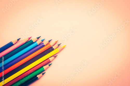 Many different colored pencils on pink background