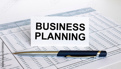 Text Business Planning on white card with blue metal pen on financial table