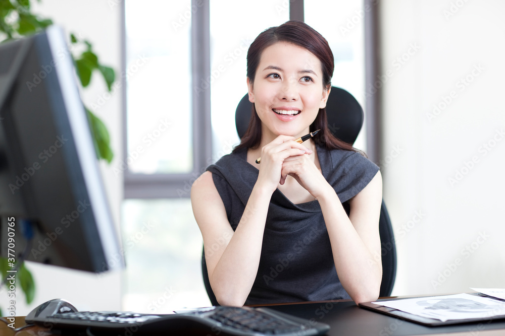 Young businesswoman sitting at desk in office Young businesswoman sitting at desk in office
