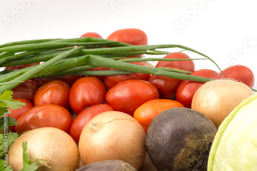 Fresh vegetables on a white background, closeup: Beet, green onions, coriander, tomato, onions, carrot, carrot. Healthy food, vegan food. Products for borscht soup.