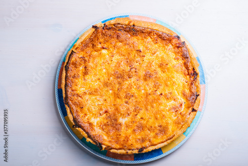 Traditional spanish cheese pie with bacon in a plate on the table. Top view