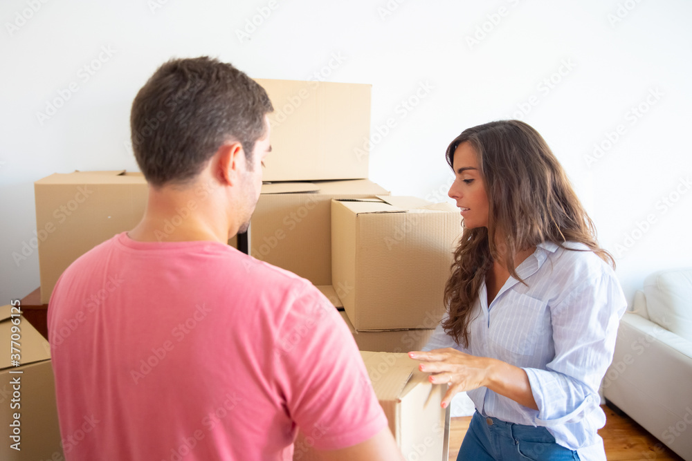 Man and woman carrying carton boxes among packages in new apartment. Transportation service or property buying concept Man and woman carrying carton boxes among packages in new apartment. Transportation service or property buying concept