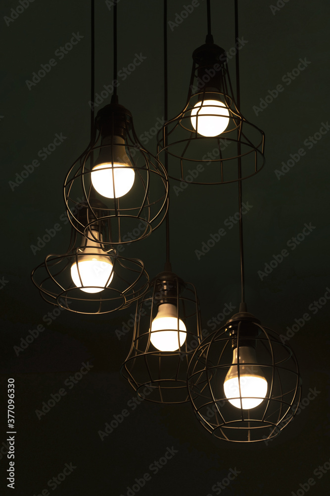hanging classic black metal light bulb in the dark night interior background hanging classic black metal light bulb in the dark night interior background