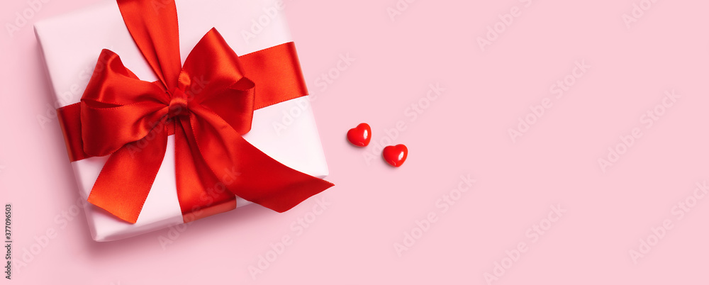 Pink gift box with red bow and two hearts on pink background . Top view. Flat lay. Pink gift box with red bow and two hearts on pink background . Top view. Flat lay.