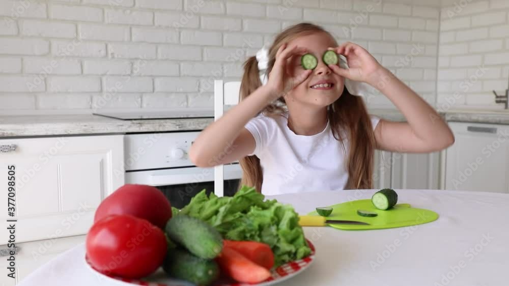 little girl cuts cucumber. Child Preparing Green Salad in Kitchen, Girl Cutting Vegetables Healthy Meal little girl cuts cucumber. Child Preparing Green Salad in Kitchen, Girl Cutting Vegetables Healthy Meal