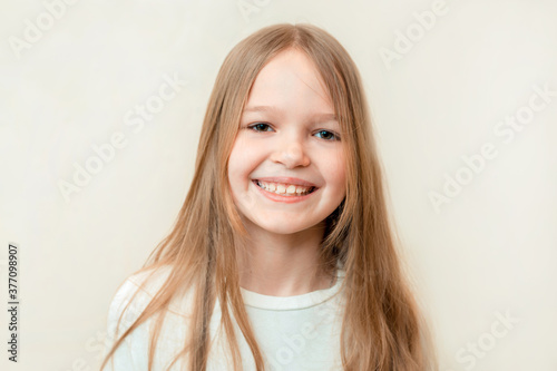 Smiling blond pretty little girl with long hier on white background