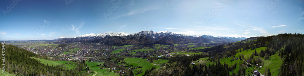 Aerial panorama, view of mountains covered with snow in summer or spring. Giewont mountain massif in the Tatra Mountains and panorama of Zakopane, Poland, Europe. High resolution panoramic view.