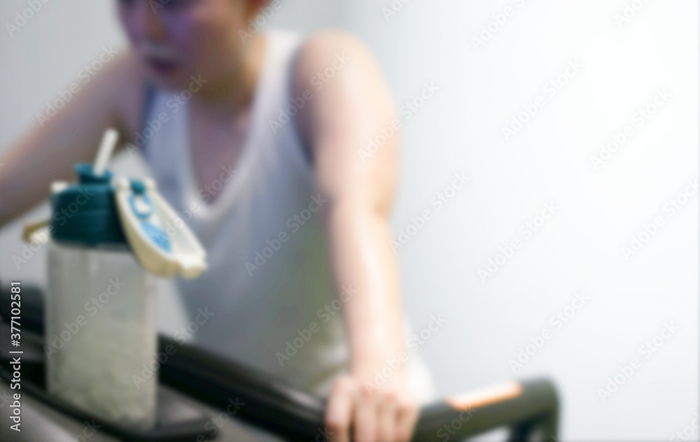 blur photo of water bottle and tired woman jogger on treadmill