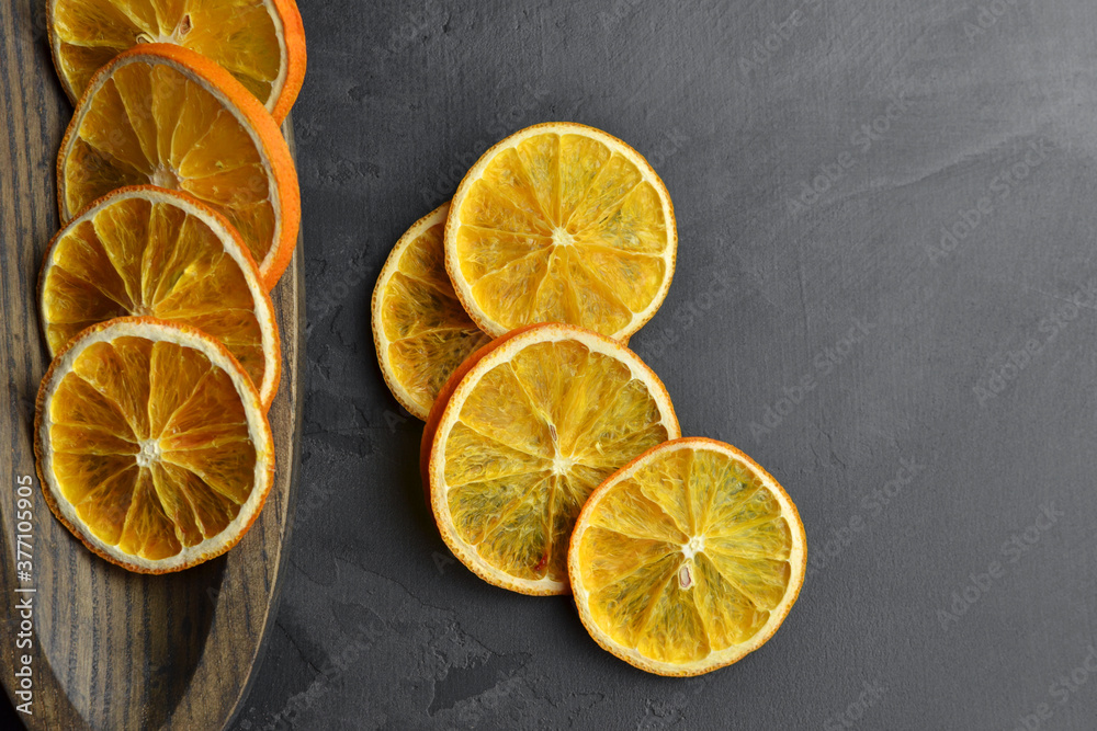 Creative layout made of dry orange slices in wooden plate on dark slate background Creative layout made of dry orange slices in wooden plate on dark slate background