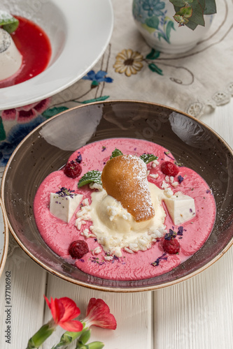 raspberry soup with ice cream and cookie on brown plate on the table at restaurant