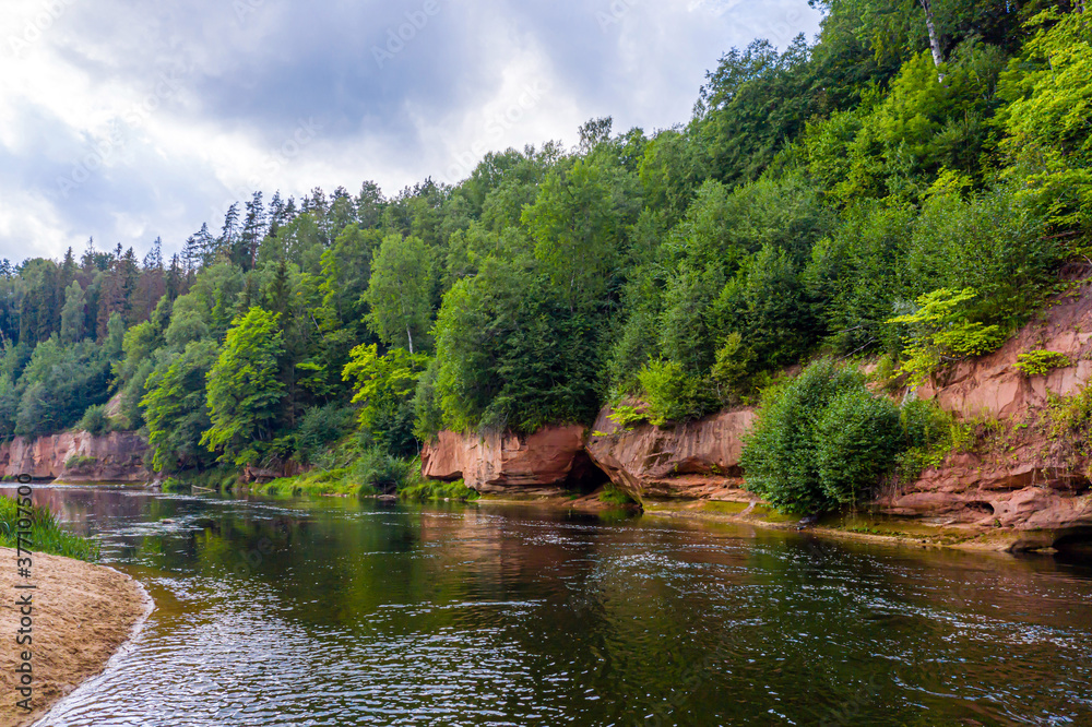 landscape with sandstone cliffs on the river bank, fast flowing and clear river water, Kuku cliffs, Gauja river, Latvia landscape with sandstone cliffs on the river bank, fast flowing and clear river water, Kuku cliffs, Gauja river, Latvia