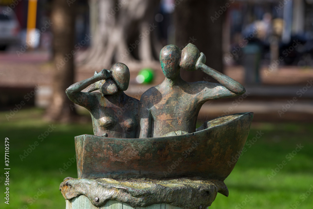 Bronze sculpture of man and women holding fish on their shoulders in small boat. The sculpture is a part of public artwork Bronze sculpture of man and women holding fish on their shoulders in small boat. The sculpture is a part of public artwork