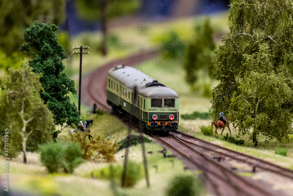 Naklejka premium Model of a locomotive of a passenger train on tracks at a bend railway diorama mockup