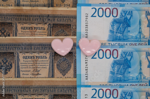 Two paper clips in the shape of hearts on the background of tsarist and modern Russian banknotes photo