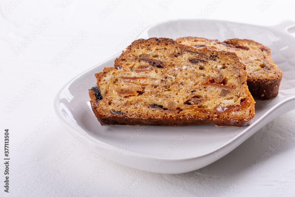 Traditional Christmas stollen cake on white background. Fruit bread with nuts, spices and dried fruit. Copy space.