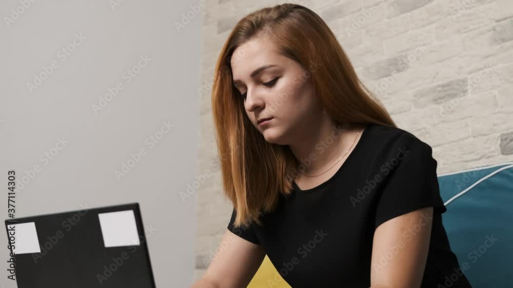 Close up of a concentrated young woman that is working at the laptop from home office. Work from home concept. Close up of a concentrated young woman that is working at the laptop from home office. Work from home concept.