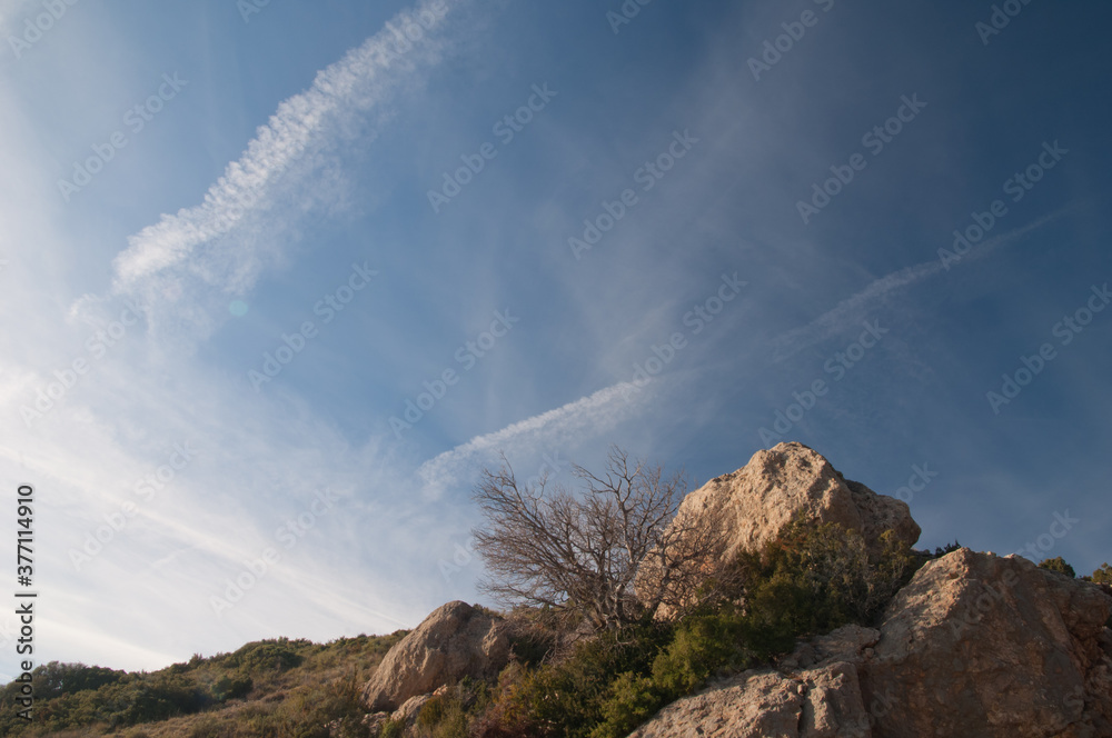 Rocks in the foreground and contrails of airplanes in the sky. Guara mountains. Huesca. Aragon. Spain.