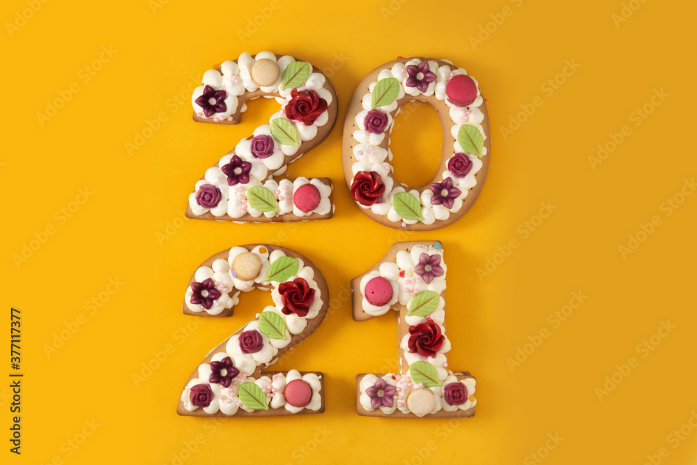 2021 cake decorated with flowers on yellow background. New year concept