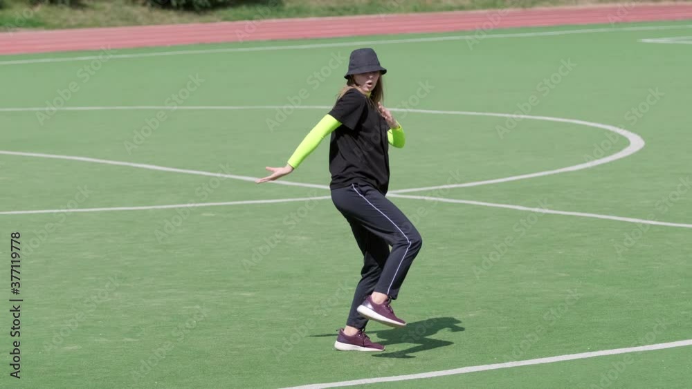 young girl performs complex acrobatic figures outdoors in a stadium. Hip hop. Urban dancing freestyle in the city. Youth subculture. Contemporary choreography. Slow motion young girl performs complex acrobatic figures outdoors in a stadium. Hip hop. Urban dancing freestyle in the city. Youth subculture. Contemporary choreography. Slow motion