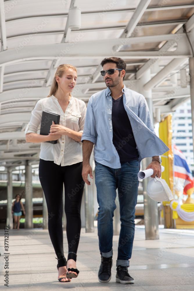 Full Length Of Happy Business People Talking While Walking On Walkway Bridge In City Full Length Of Happy Business People Talking While Walking On Walkway Bridge In City