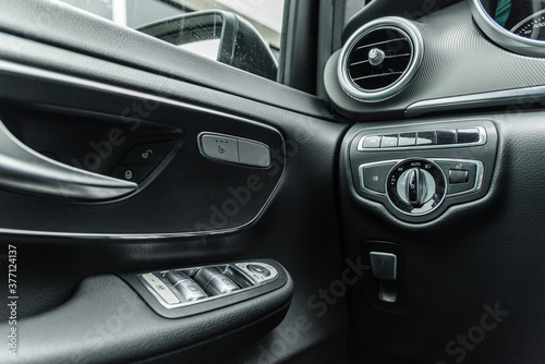 Inside look of low angle to a light switch and ventilations system with power window swith and door open handle of a modern german car. © Dubrafoto