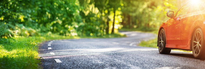 red car on asphalt road in summer