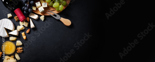 Schilderij op canvas Menu frame with different types of cheese, honey, grapes and wine on black backg