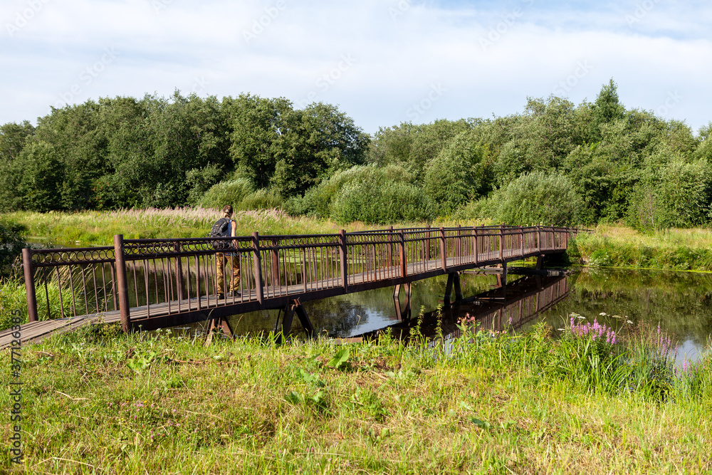 A tourist walks on a pedestrian wooden bridge over the river