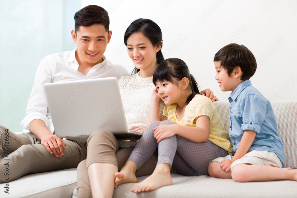 Cheerful young family using laptop at home Cheerful young family using laptop at home