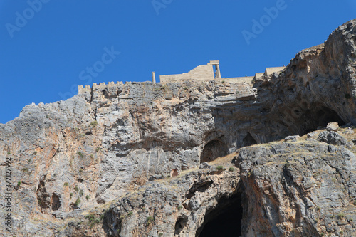 Cliff in Lindos Greece with Blue Sky. Steep cliff with small caves. Above beautiful blue skies