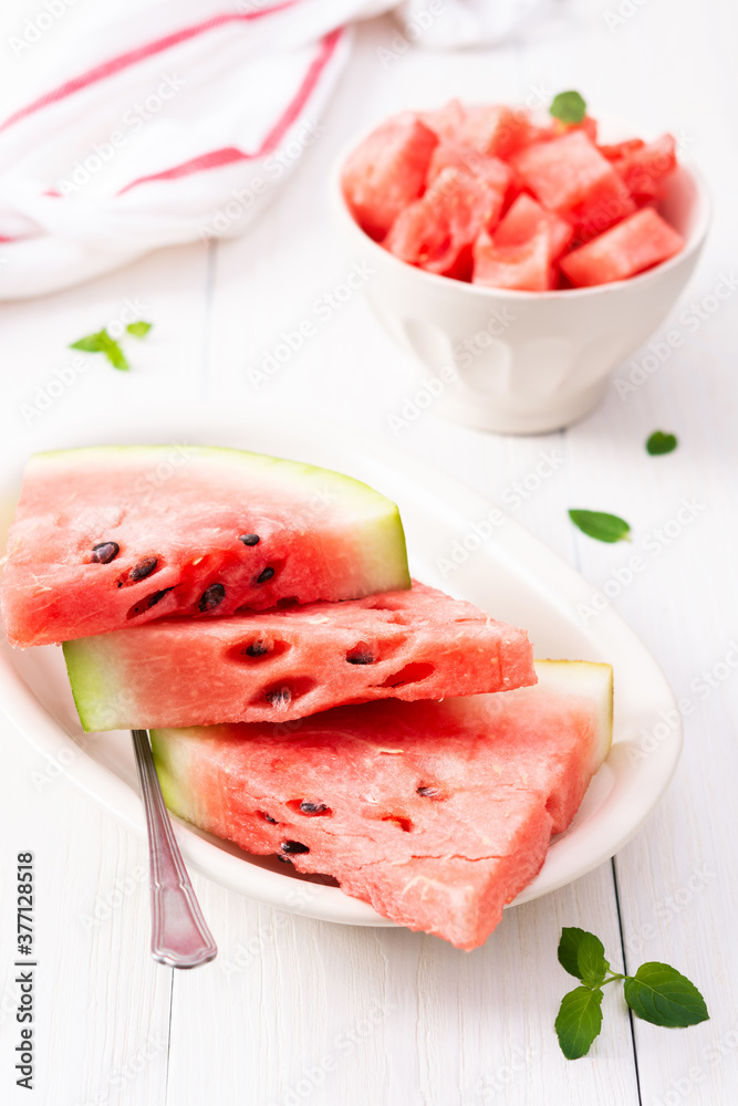Juicy ripe sweet red watermelon slices with mint in a plate on a white background