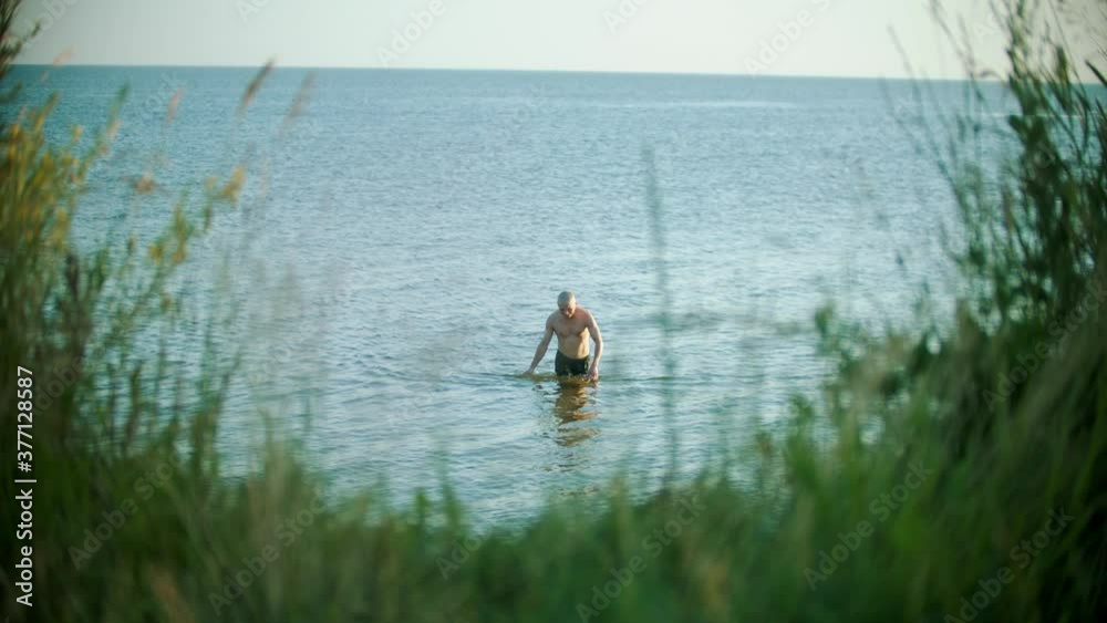 Young bald caucasian man walking out of the river Young bald caucasian man walking out of the river