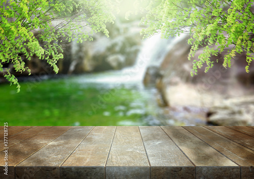 Empty wooden table top over abstract blur of waterfall. Product display mockup