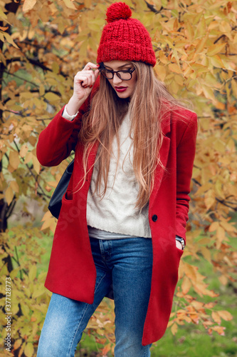 Fashion photo of  blond  woman with long hairs walking in sunny  autumn park in trendy casual outfit.